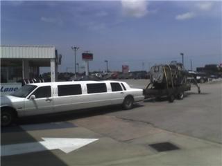 1992 Ford Bronco - A white limousine is seen towing a trailer loaded with equipment on a sunny day.