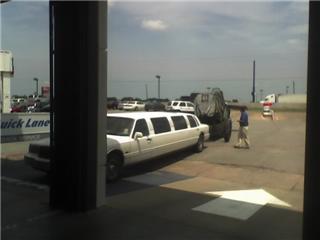 1992 Ford Bronco - A white limousine is parked on pavement, with a trailer and a person nearby.
