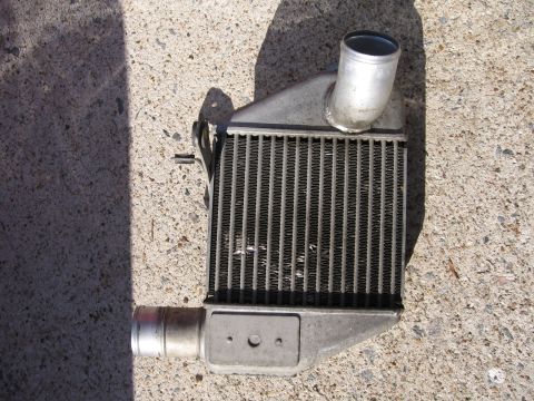 1991 Mitsubishi 3000GT - A close-up view of an intercooler, likely removed from a vehicle, rests on a concrete surface.