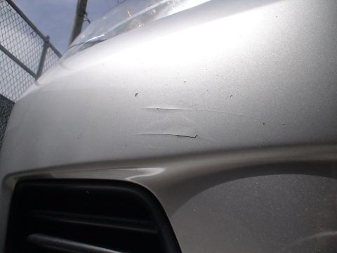 1993 Ford C-350 (Centurion Conversions) - Scratches are visible on the front bumper of a silver vehicle.