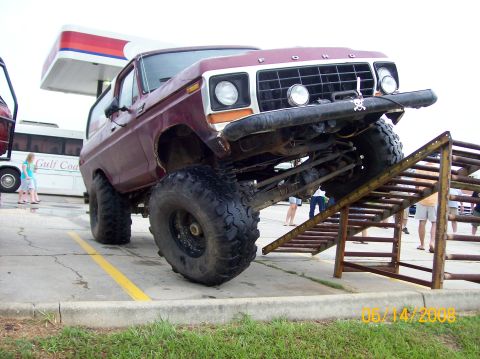 1978 Ford Bronco - This modified Ford Bronco is tackling an off-road obstacle course, its lifted suspension and large tires.