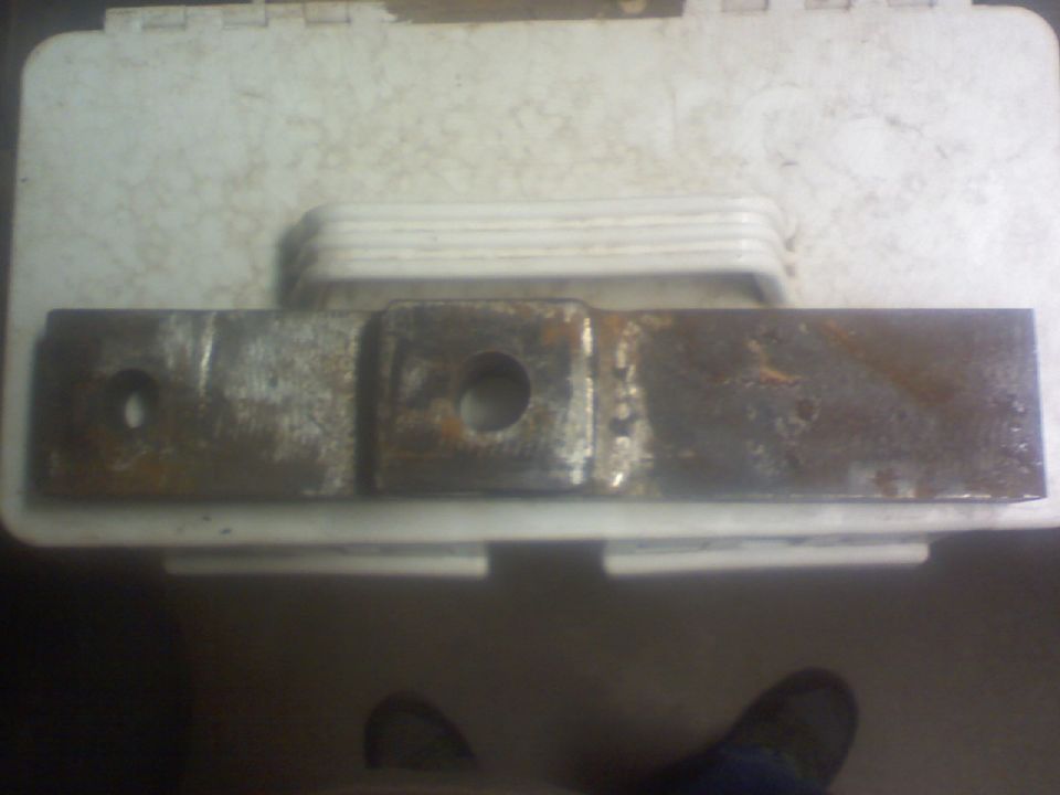 rusted metal bracket with two holes, one round and one square-ish
