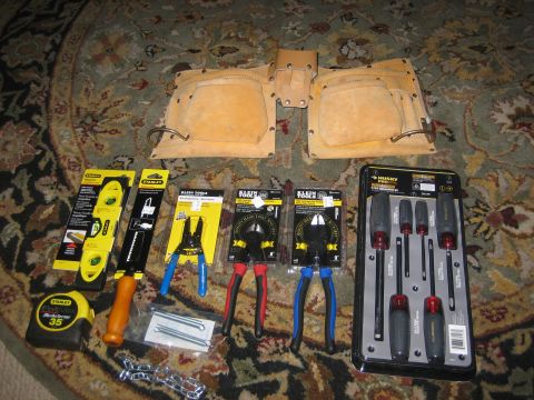 1995 Ford Bronco - A collection of hand tools including a tool belt, levels, pliers, wire cutters, screwdrivers, and a tape measure are laid out on a patterne…