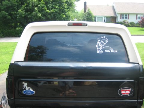 1995 Ford Bronco - Rear view of a black Ford Bronco with a white top, displaying "City Boys" and Ford decals on the tailgate.