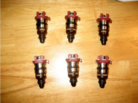 1993 Ford Probe - Six fuel injectors are laid out on a wooden surface, with a 'Supermotors.net' watermark visible.