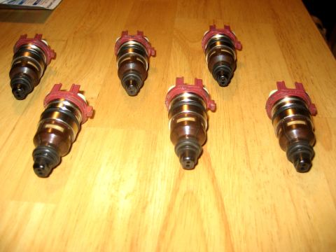 1993 Ford Probe - Seven fuel injectors are laid out on a wooden surface, with a website address visible in the lower right corner.