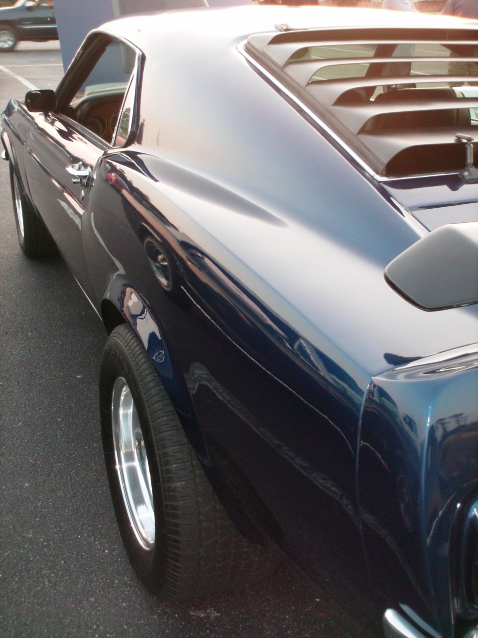 Dark blue classic car, rear quarter panel and side view. Hood is up