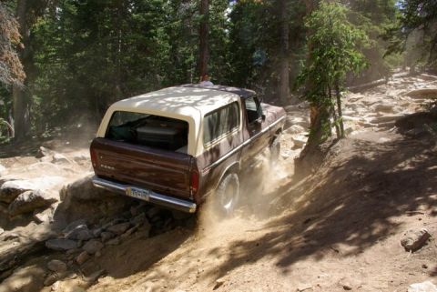 1995 Ford Bronco - This SUV is shown tackling a challenging, rocky off-road path with dust kicking up.