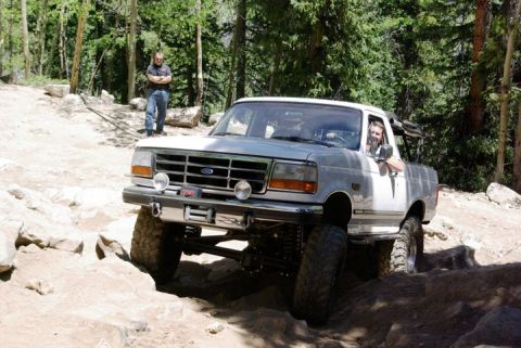 1995 Ford Bronco - Ford F-250 truck tackling a challenging off-road trail in a wooded area.