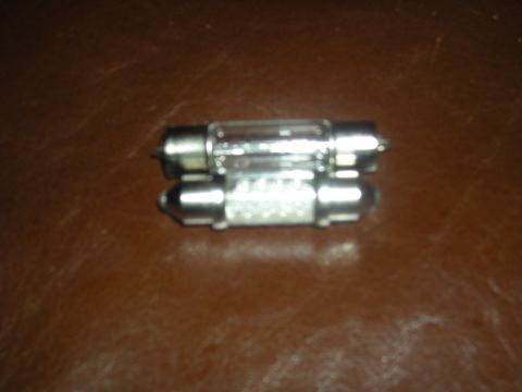 1986 Ford Bronco - Two automotive festoon light bulbs are shown against a brown background.