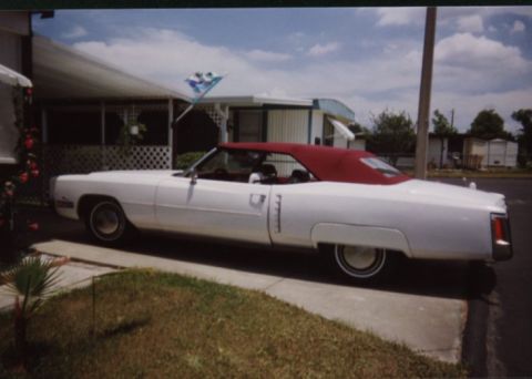 1972 Pontiac Grand Prix - This white convertible with a red top is parked in front of a mobile home, with a flag flying in the background.