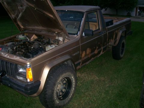 1993 Jeep Cherokee - This Jeep Comanche pickup truck, seen with its hood open, displays significant rust on its lower body panels.
