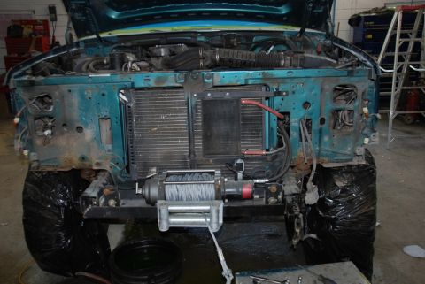 1996 Ford Bronco - The front end of a vehicle is disassembled, revealing the engine bay and radiator, with a winch installed.