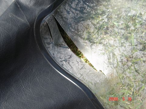 1993 Ford Bronco - The plastic window on this soft top has a significant tear, revealing the grassy ground beneath.