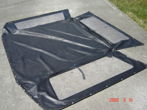 1993 Ford Bronco - A black soft top with clear windows is displayed on a concrete surface.