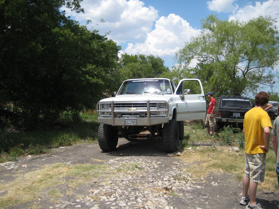 White pickup truck with lifted suspension and aftermarket bumper, driver's door open