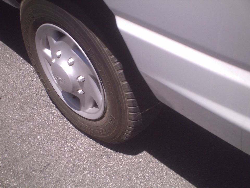 Close-up of a silver wheel and white side panel on a vehicle