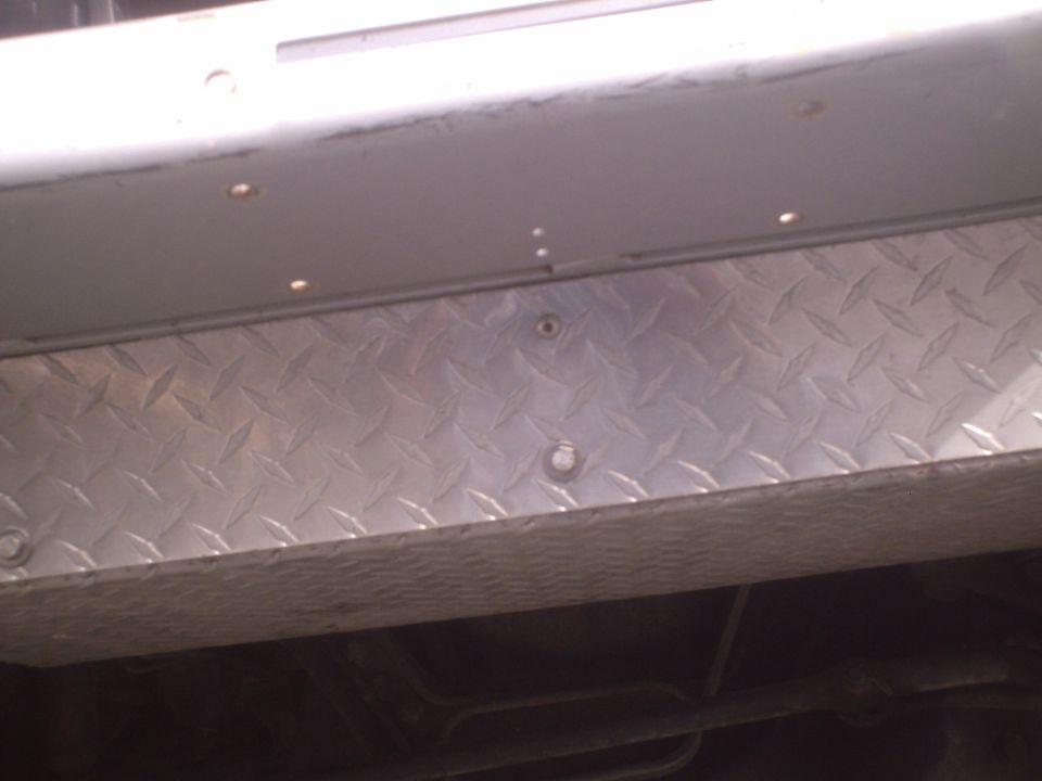 Diamond plate trim below a silver body panel on a vehicle