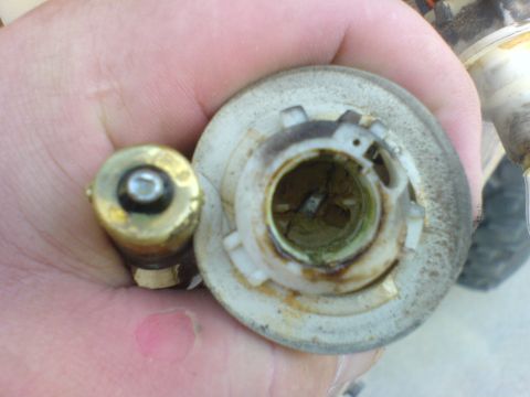 1986 Ford Bronco - A close-up shows a brass light bulb and its corresponding socket, likely for a vehicle's lighting system.