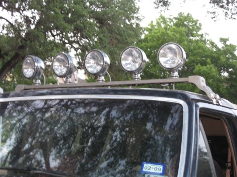 1990 Ford Bronco - Auxiliary lights mounted on a roof rack are visible on a vehicle.