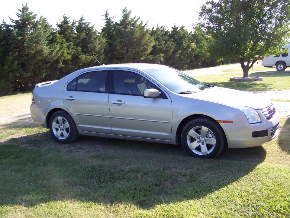 Silver Ford Fusion sedan, passenger side view, parked on grass