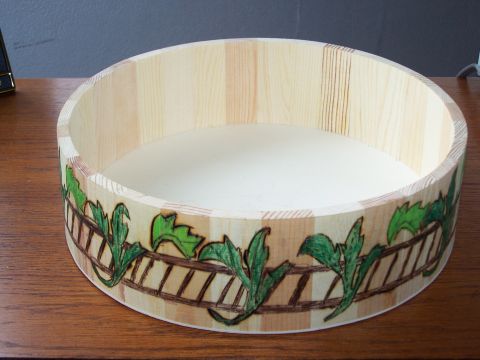 1995 Ford C-350 (Centurion Conversions) - A wooden bowl with a decorative band of green leaves and a brown fence pattern is shown.