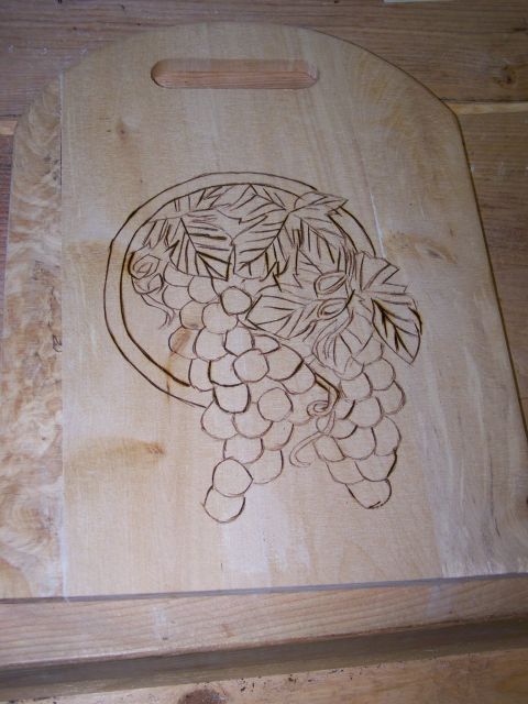 1995 Ford C-350 (Centurion Conversions) - A wooden cutting board features an unfinished pyrography design of grapes and leaves.