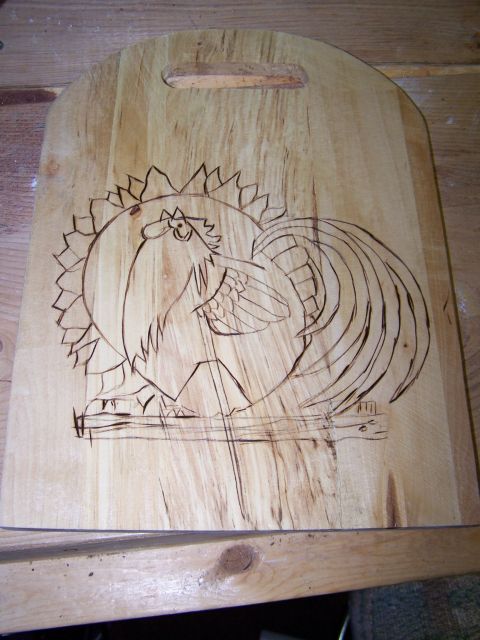 1995 Ford C-350 (Centurion Conversions) - A wooden cutting board features a pyrography design of a rooster with a sun-like halo.