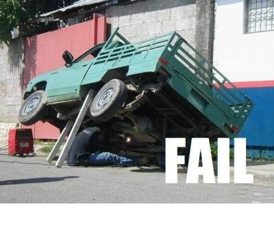 2000 Mercury Grand Marquis - A precarious repair situation with a truck tilted and a person working underneath.