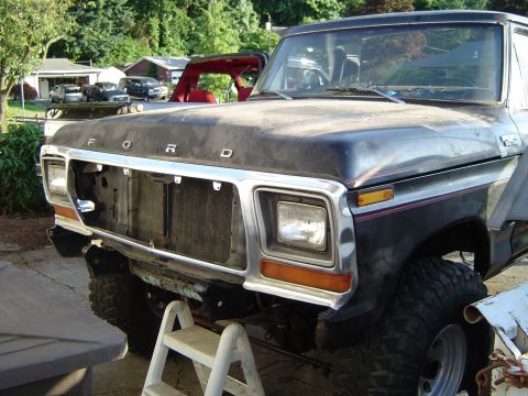 1979 Ford Bronco - Front view of a black 1979 Ford Bronco, missing its grille, with a red interior visible.