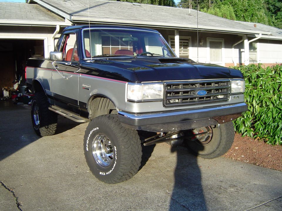 Black and silver lifted Ford Bronco, top removed, in a driveway