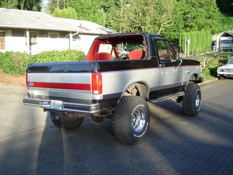 1989 Ford Bronco - This 1989 Ford Bronco features a two-tone silver and black paint scheme with a red interior and lifted suspension.