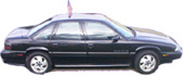 1972 Pontiac Grand Prix - Side view of a dark sedan flying an American flag from its roof.