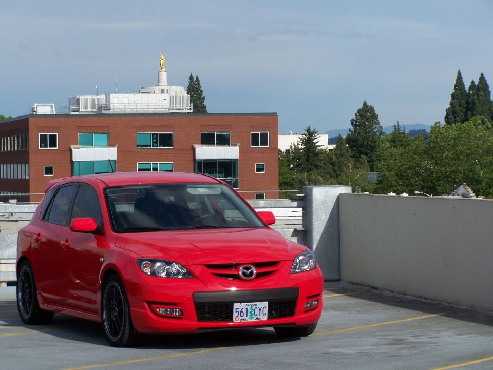 Red 2007 Mazda 3 hatchback, front 3/4 view, parked on a rooftop