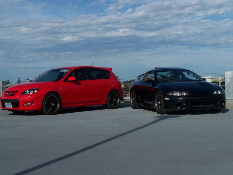 Red 2007 Mazda 3 hatchback and black coupe parked side-by-side