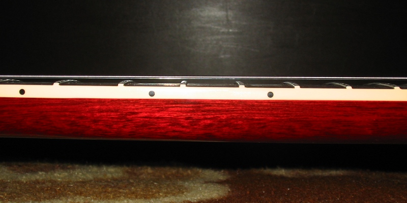 Red guitar neck with frets and fret markers