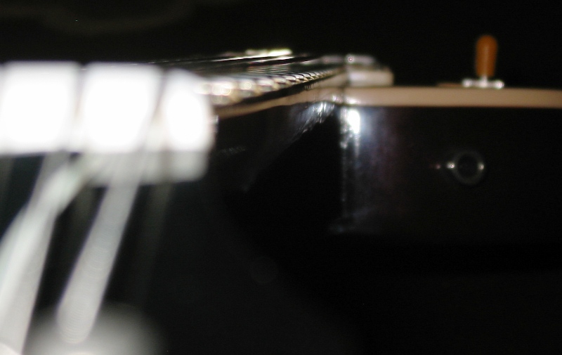 Close-up of guitar strings and body with a toggle switch