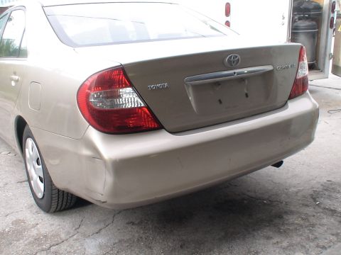 1993 Ford C-350 (Centurion Conversions) - Rear view of a tan Toyota Camry with damage to the bumper.