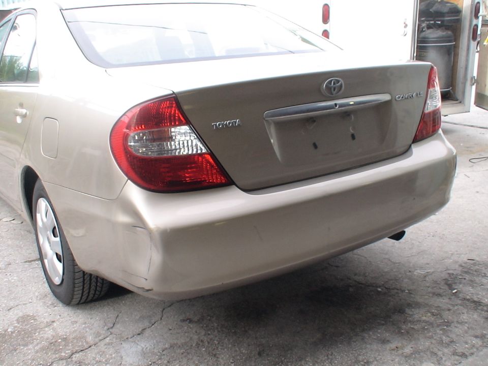 Tan Toyota Camry with dented rear bumper and visible Toyota and Camry badging