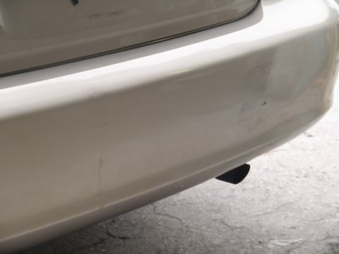 1993 Ford C-350 (Centurion Conversions) - Close-up view of the rear bumper and exhaust pipe of a white vehicle.
