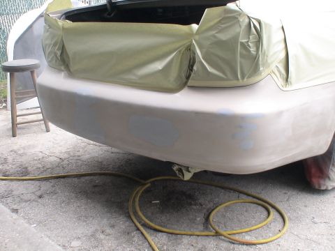 1993 Ford C-350 (Centurion Conversions) - The rear bumper of a car is being prepped for painting, with masking tape covering the trunk area.