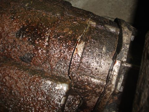 1989 Ford Bronco - This heavily corroded metal part shows a significant crack, indicating potential failure.