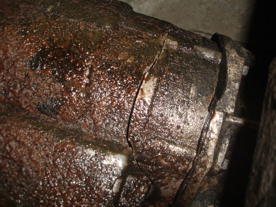 Close-up of a heavily corroded and cracked metal component, possibly part of a vehicle's drivetrain
