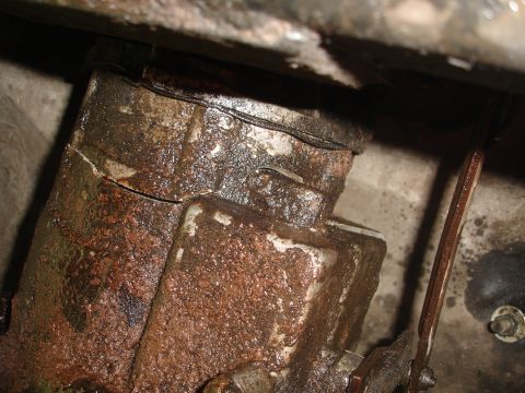 1989 Ford Bronco - This close-up shows a heavily soiled and cracked metal component, likely an engine part, with visible oil residue.