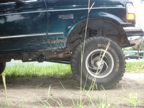 1989 Ford Bronco - Side view of a 1989 Ford Bronco, with mud splatters visible on the lower body panel and fender.