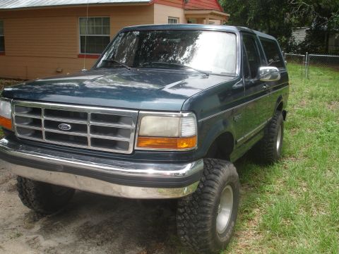 1989 Ford Bronco - This Ford Bronco features a prominent grille and large tires, parked outdoors near a residential building.