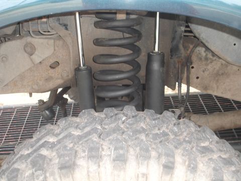 1989 Ford Bronco - This image shows the front suspension components of a vehicle, including a tire, coil spring, and shock absorber.