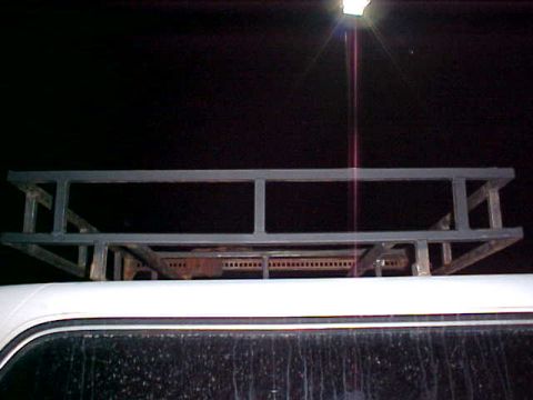 1987 Ford Bronco - A custom-built roof rack is shown mounted on the top of a white vehicle. The rack appears to be made of metal tubing.