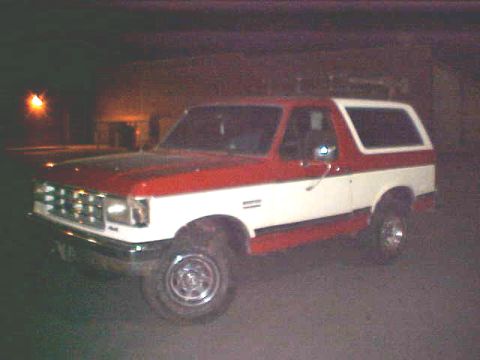 1987 Ford Bronco - This 1987 Ford Bronco is seen from the front-left at an angle, parked outdoors at night.