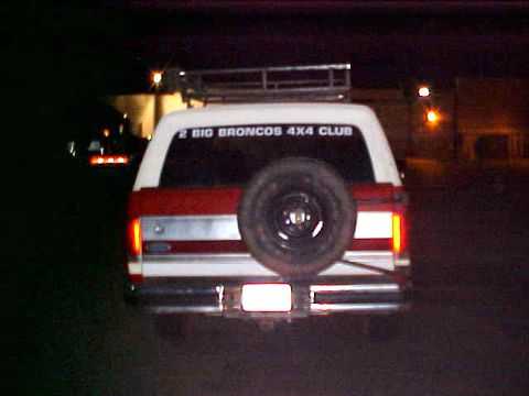 1987 Ford Bronco - This 1987 Ford Bronco is seen from the rear at night, a spare tire and a club decal on the window.